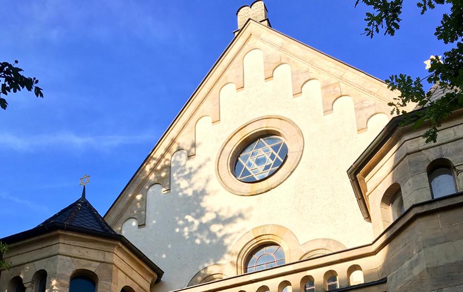 Ein Teil der Synagoge Straubingen ist aus der Untersicht fotografiert mit blauem Himmel im HIntergrund.