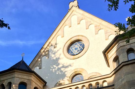 Ein Teil der Synagoge Straubingen ist aus der Untersicht fotografiert mit blauem Himmel im HIntergrund.